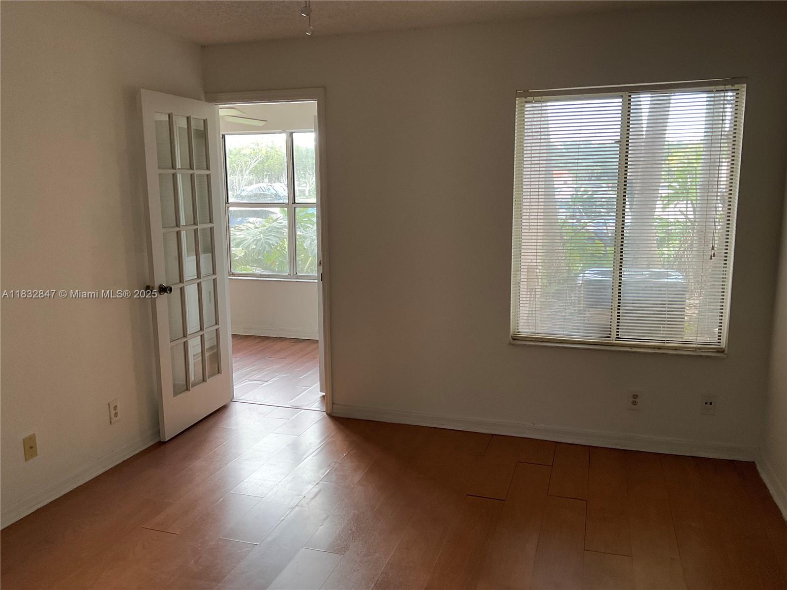 3320 Pinewalk Drive North, Unit 1715 Margate, FL 33063 - Photo 18 of 35 an empty room with wooden floor and windows