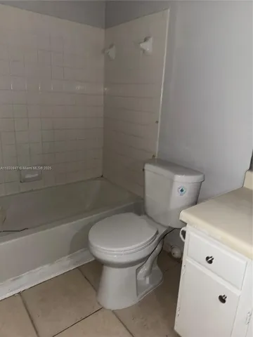 an empty room with wooden floor and a kitchen