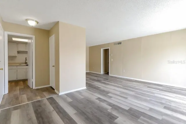 a view of a livingroom with wooden floor and a bathroom