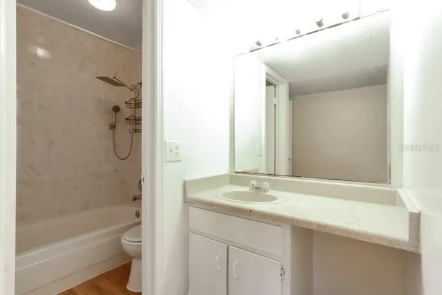 a bathroom with a granite countertop sink a toilet and shower