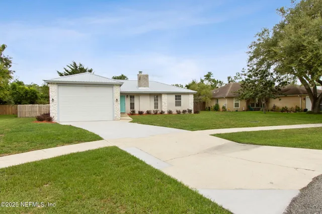 a view of a house with a big yard plants and large trees