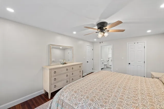 a bedroom with a bed chandelier dresser and a window