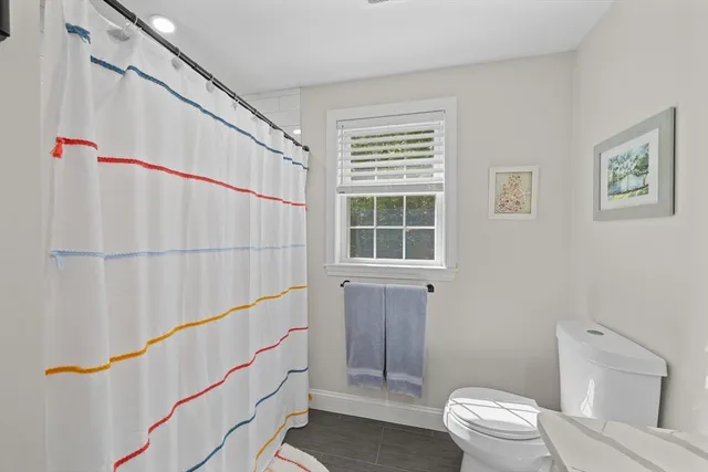 a bathroom with a sink a toilet a window and shower