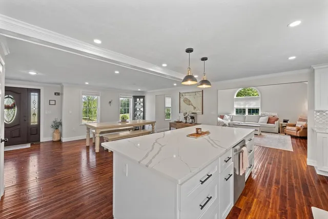 a view of a kitchen with kitchen island a stove a sink a refrigerator and a dining table with wooden floor