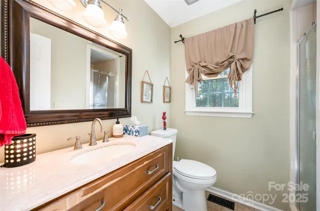 a bathroom with a granite countertop sink mirror vanity and toilet