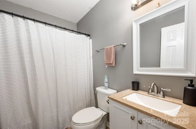 a bathroom with a granite countertop sink vanity mirror and toilet