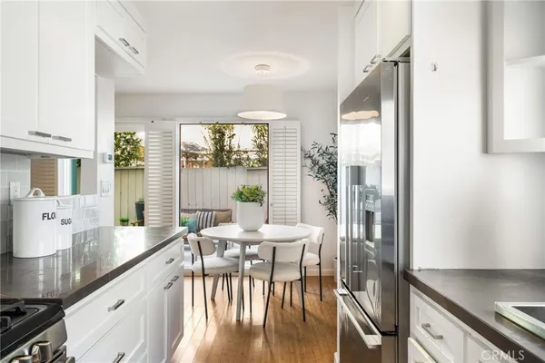 a kitchen with stainless steel appliances granite countertop a table chairs and a large window