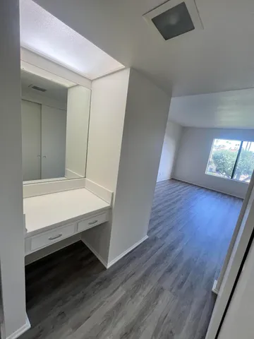 a view of a hallway and an empty room with wooden floor