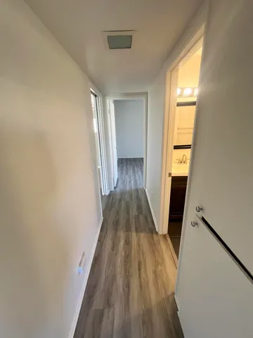 a view of a hallway with wooden floor and staircase