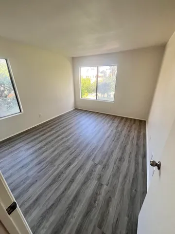 an empty room with wooden floor and windows