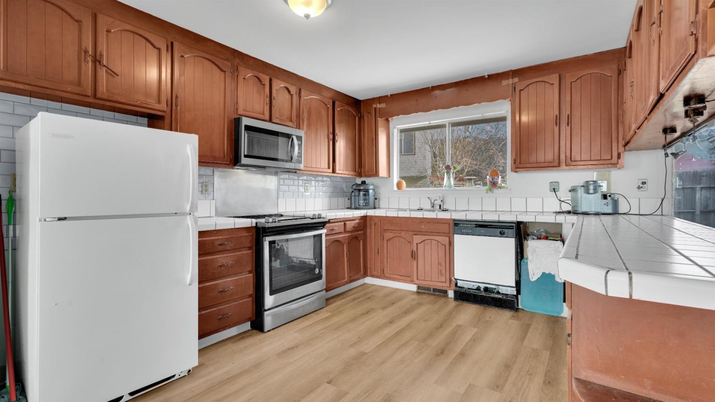 6530 Simson Street Oakland, CA 94605 - Photo 5 of 14 a kitchen with granite countertop wooden floors stainless steel appliances a sink and a window