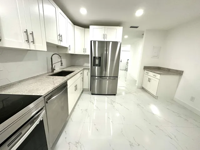a kitchen with granite countertop a refrigerator and a sink