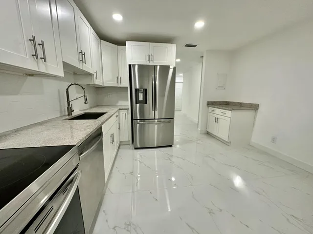 a kitchen with granite countertop a refrigerator and a sink