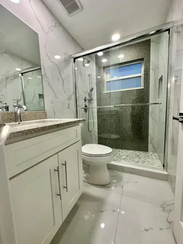 a bathroom with a shower sink vanity and toilet