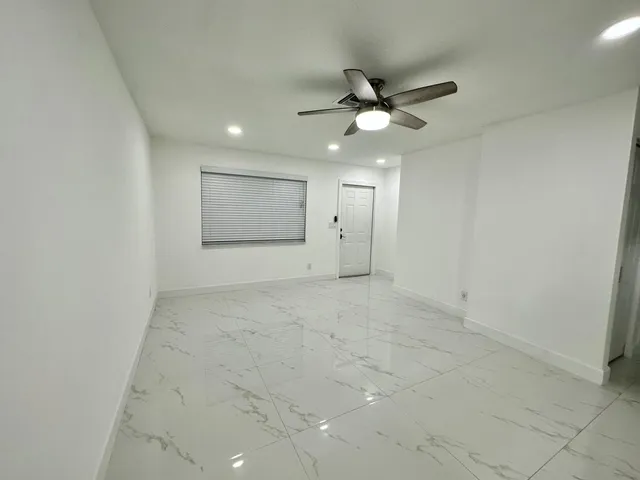 an empty room with a ceiling fan and window