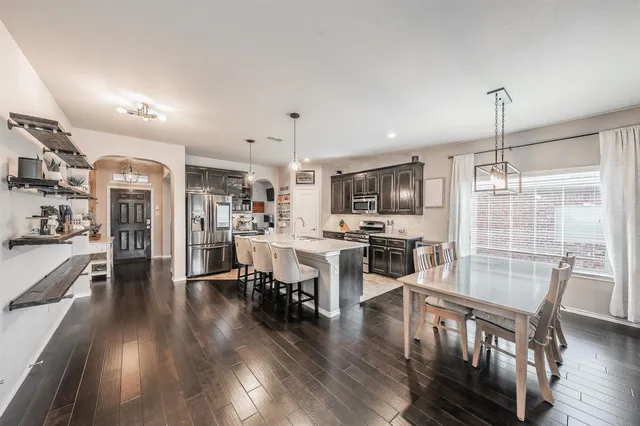 a view of a dining room and livingroom with furniture wooden floor kitchen chandelier