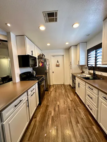 a large kitchen with stainless steel appliances a large counter top a stove a sink and a refrigerator