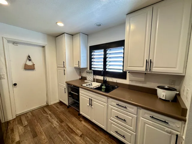 a kitchen with stainless steel appliances granite countertop a sink and cabinets with wooden floor
