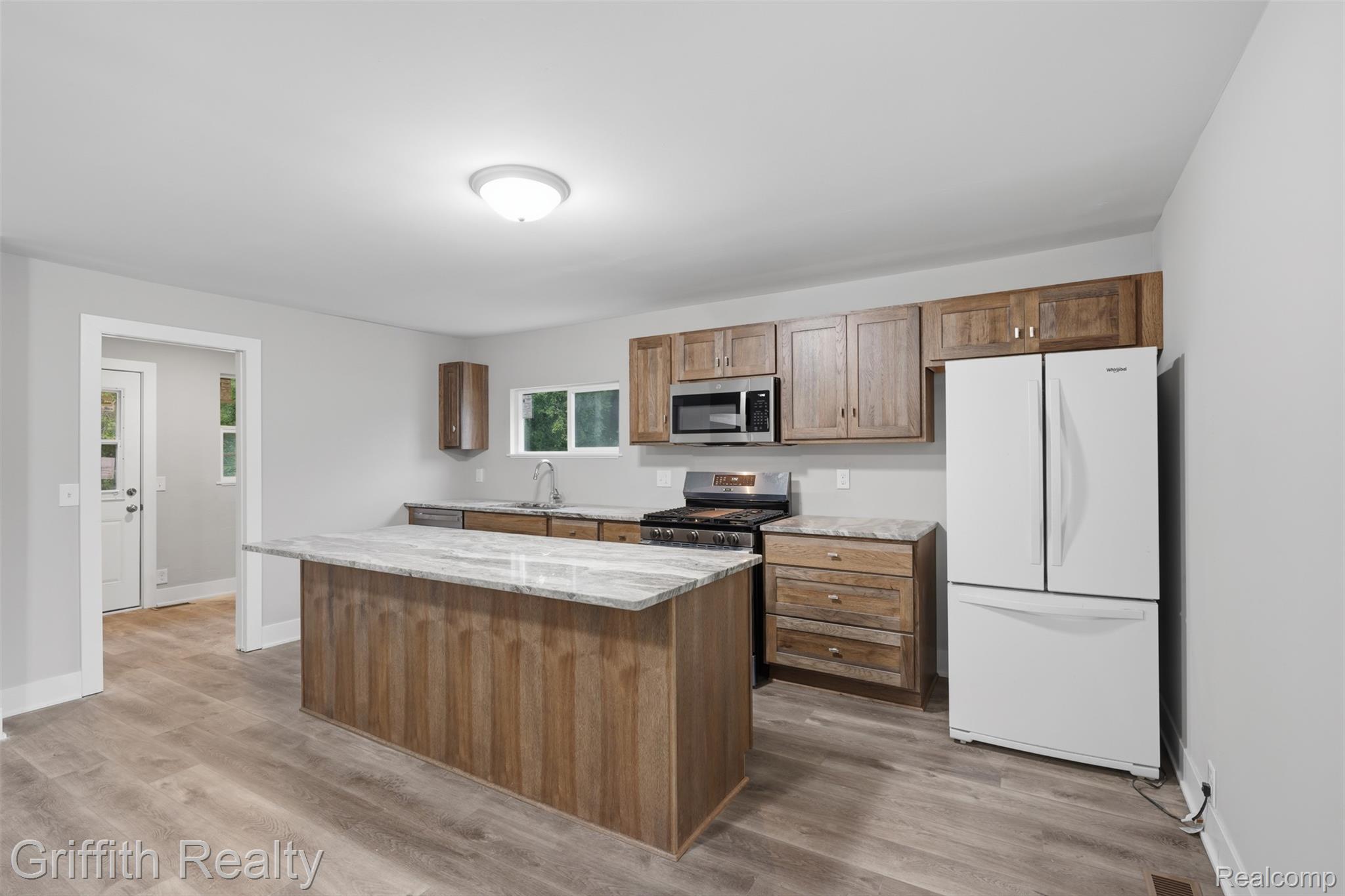 5820 Mack Road Howell, MI 48855 - Photo 16 of 60 Kitchen featuring wood-finish cabinetry, a large center island with a light-toned countertop, and wood-finish flooring