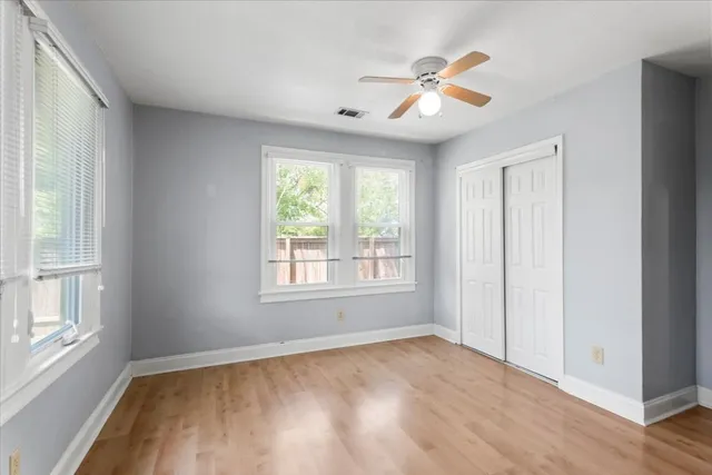 a view of empty room with wooden floor and fan