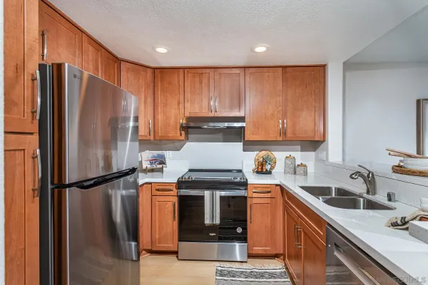 a kitchen with stainless steel appliances granite countertop a refrigerator stove top oven and sink