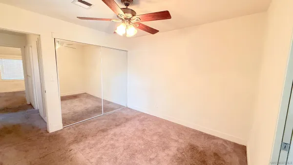 an empty room with a ceiling fan and a window