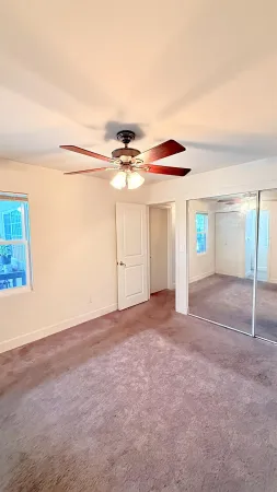 a view of empty room with window and ceiling fan