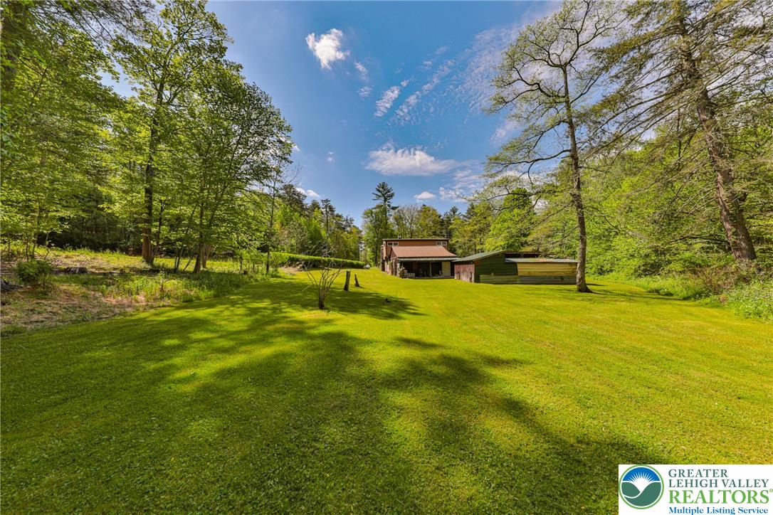 331 Cranberry Creek Road Cresco, PA 18326 - Photo 65 of 95 A verdant, open field extends towards a charming rustic structure, nestled among mature trees.