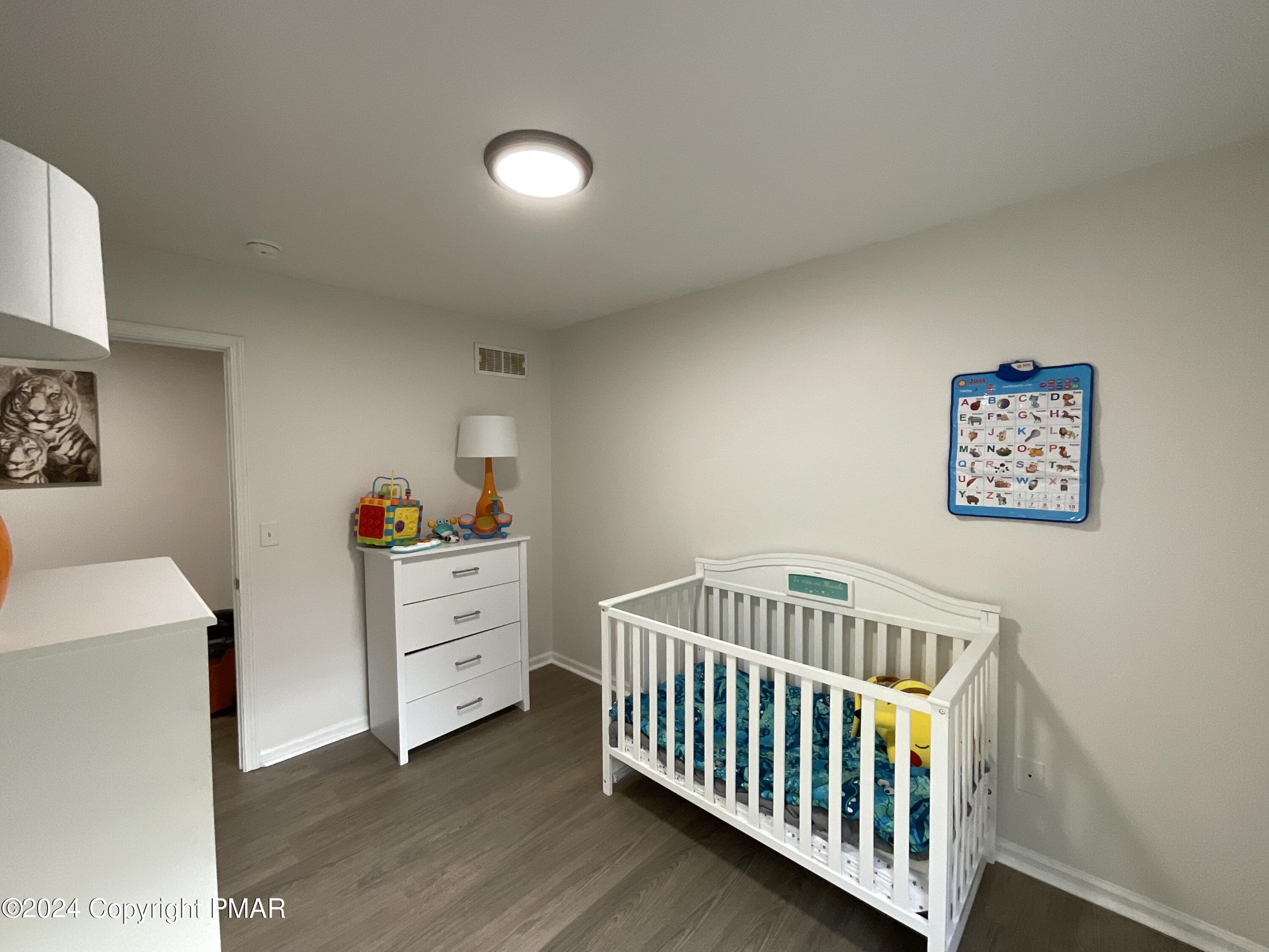 146 Hound Road Dingmans Ferry, PA 18328 - Photo 40 of 50 a bedroom with a baby bed a desk and chair with wooden floor
