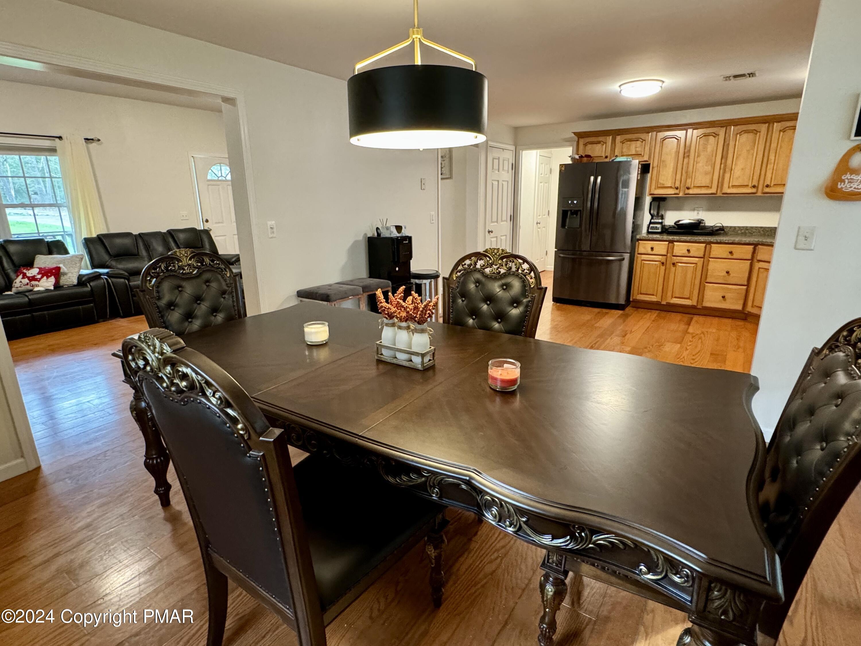 146 Hound Road Dingmans Ferry, PA 18328 - Photo 8 of 50 a kitchen with stainless steel appliances granite countertop a refrigerator a stove a dining table and chairs with wooden floor
