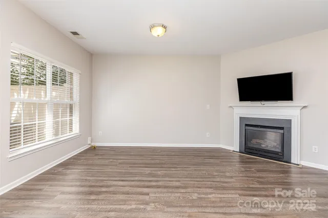 a view of empty room with wooden floor and fireplace