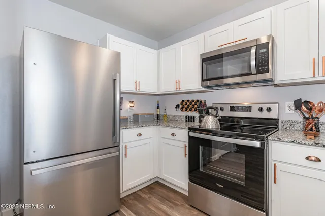 a kitchen with stainless steel appliances a refrigerator stove and white cabinets