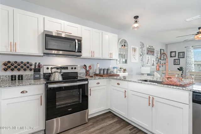a kitchen with granite countertop white cabinets and stainless steel appliances