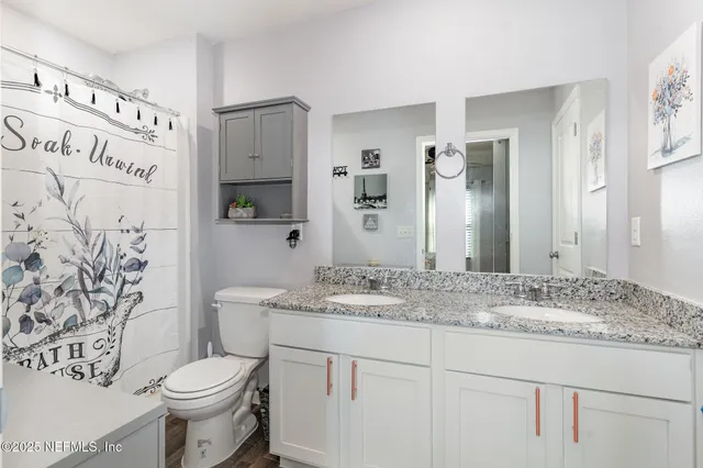 a bathroom with a granite countertop sink toilet and mirror
