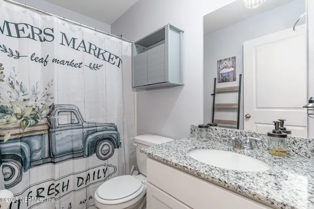 a bathroom with a granite countertop toilet sink and mirror