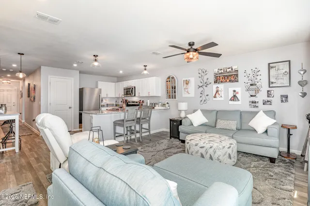 a living room with furniture kitchen view and a chandelier