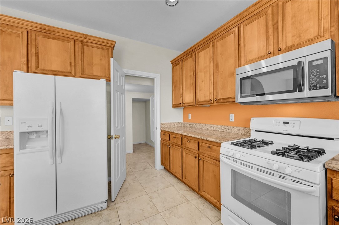 977 Sparkling Light Street Henderson, NV 89052 - Photo 33 of 75 This bright kitchen features ample wood cabinetry, granite countertops, and modern appliances.