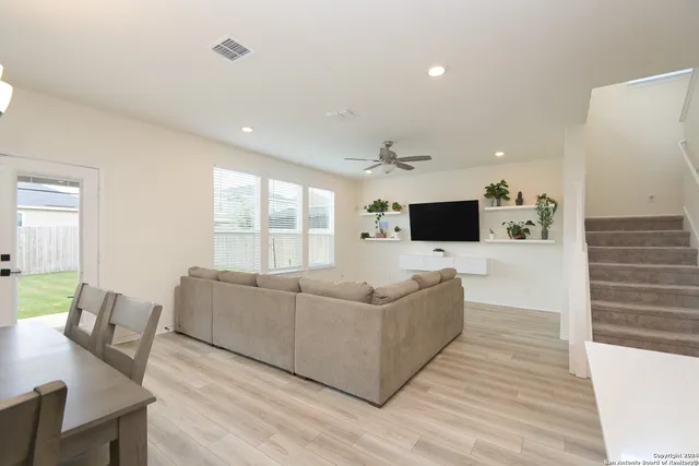a living room with furniture a flat screen tv and a wooden floor