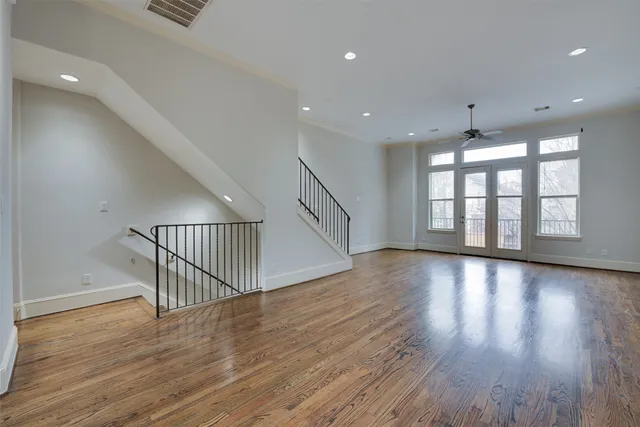 a view of an empty room with wooden floor and fan