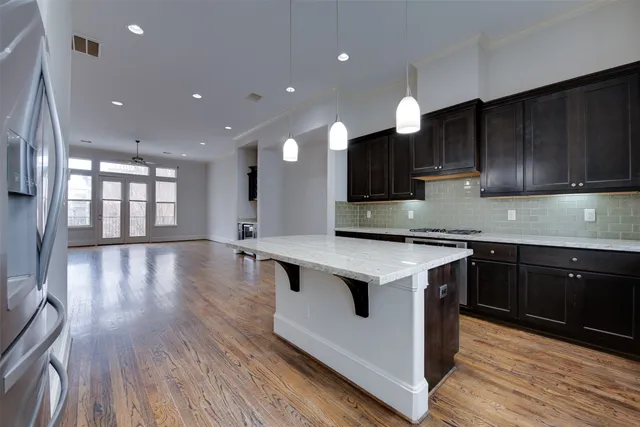 a kitchen with stainless steel appliances granite countertop a sink a stove and a wooden floors