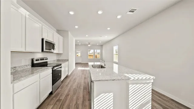 a large kitchen with granite countertop a large counter top appliances and cabinets