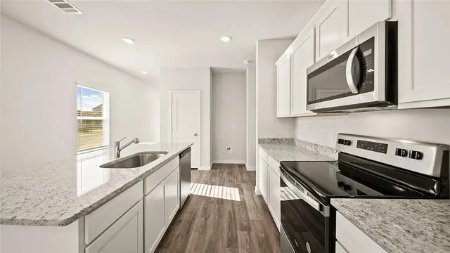 a kitchen with stainless steel appliances granite countertop a stove a sink and a microwave