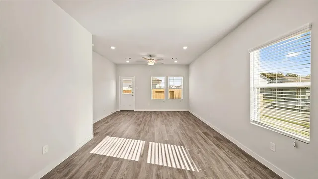 a view of empty room with wooden floor and fan