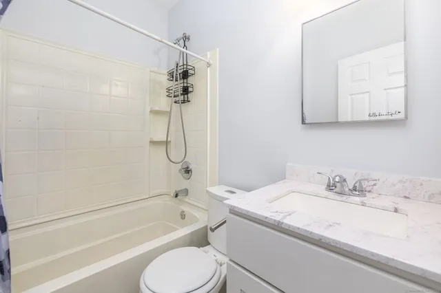 a bathroom with a granite countertop bathtub shower sink vanity and toilet