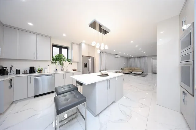 a large white kitchen with cabinets a sink dishwasher a stove and a refrigerator with wooden floor