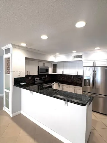 a kitchen with stainless steel appliances granite countertop a sink and a refrigerator