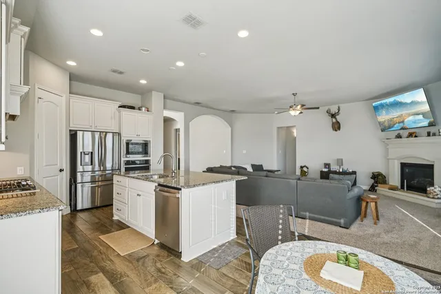 a kitchen with stainless steel appliances kitchen island granite countertop a stove refrigerator and cabinets