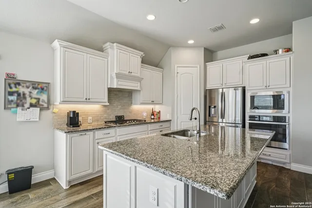 a kitchen with stainless steel appliances granite countertop a sink refrigerator and cabinets