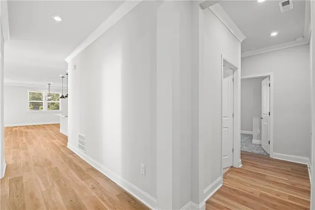 a view of an empty room with wooden floor and a ceiling fan