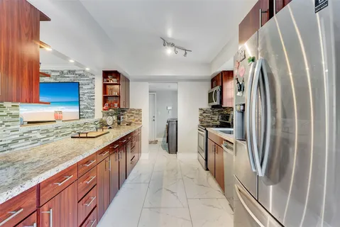 a large kitchen with stainless steel appliances granite countertop a sink stove and refrigerator